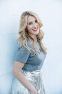 headshot of a blond woman leaning against a wall