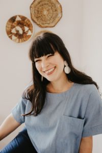 smiling woman in front of baskets on the wall