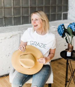 blond woman sitting in a chair with a hat