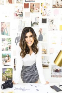 smiling woman standing in front of wall with pictures on it
