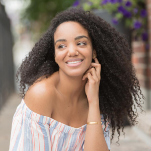 woman with dark, curly hair and an off-the-shoulder shirt
