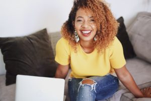 laughing woman on sofa with open laptop by her